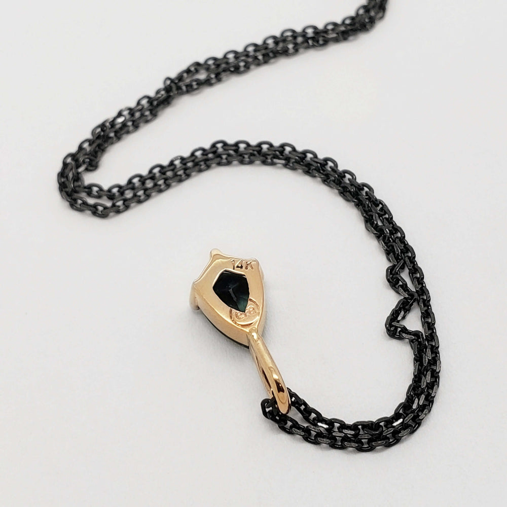 Back view of 14kt yellow gold shield pendant with green sapphire and black chain
