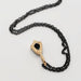Back view of 14kt yellow gold shield pendant with green sapphire and black chain