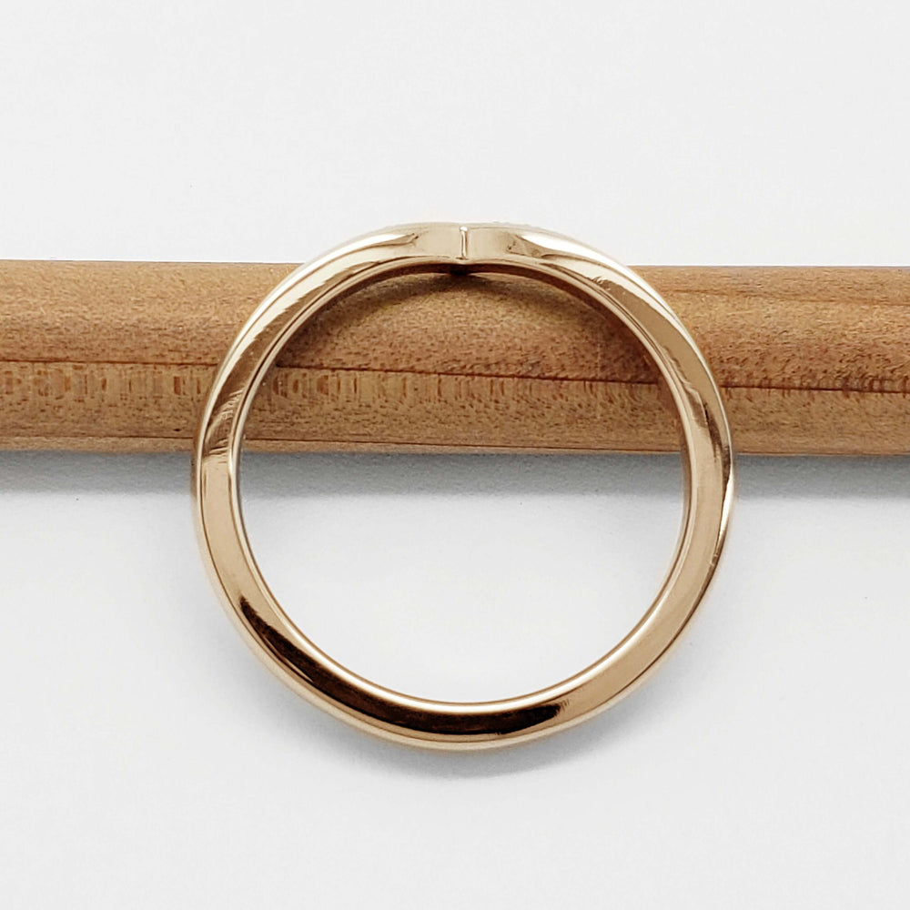 Back view of yellow gold chevron wedding ring on a wooden pencil