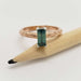 Baguette cut teal Australian sapphire ring in engraved 14kt rose gold, displayed on pencil