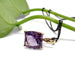 Barrel-cut purple amethyst pendant in yellow gold with black chain, styled with green leaf