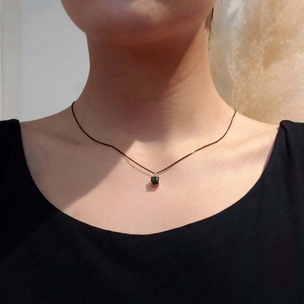 Barrel cut green tourmaline pendant in yellow gold on model's neck