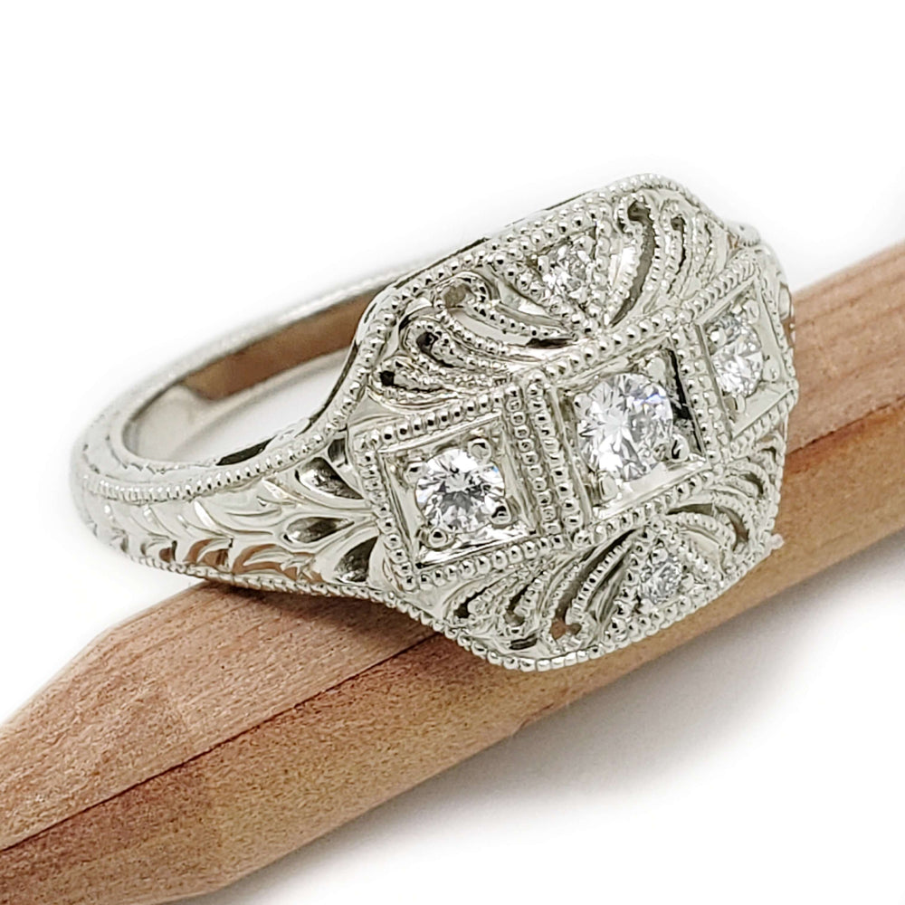 Bead-set diamond Art Deco engagement ring in 19kt white gold, shown on a wooden stick