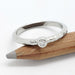 Bezel-set Canadian diamond hammered white gold ring resting on pencil