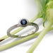 Bezel-set Montana sapphire ring in white gold with engraved band, shown with greenery
