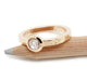 Bezel-set rose cut diamond ring in 14kt rose gold resting on a pencil