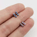 Sapphire bar stud earrings in blue and purple shown on hand for scale