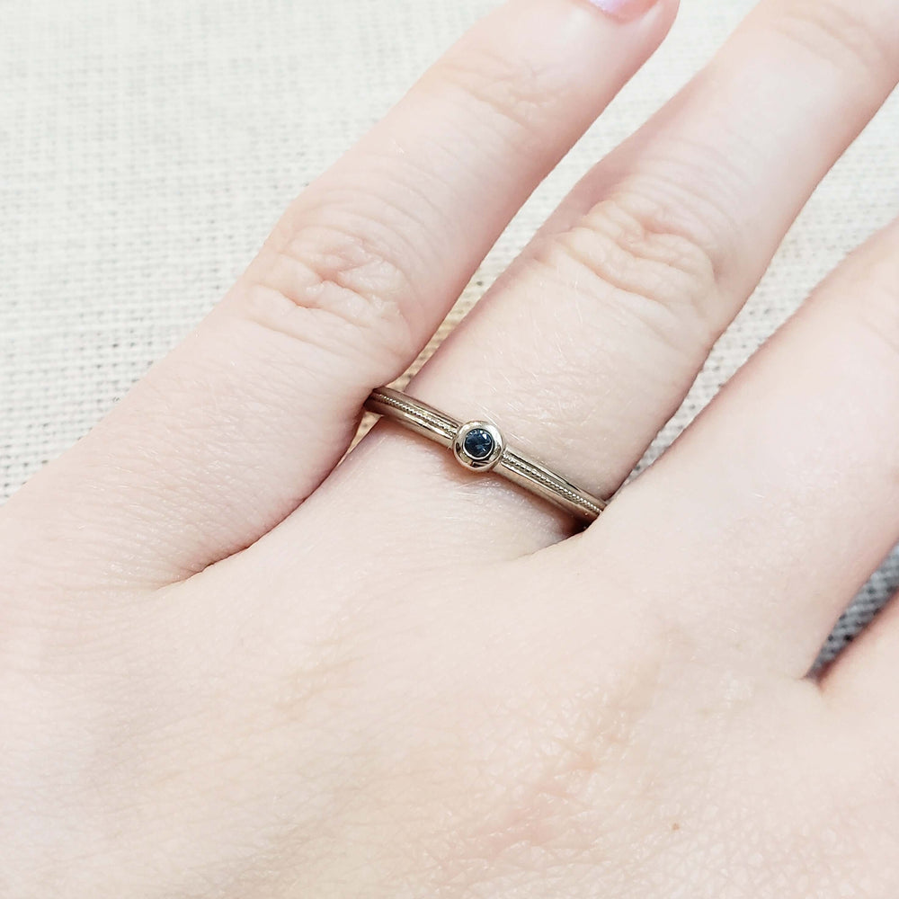 Blue sapphire stacking ring in 14k white gold worn on hand