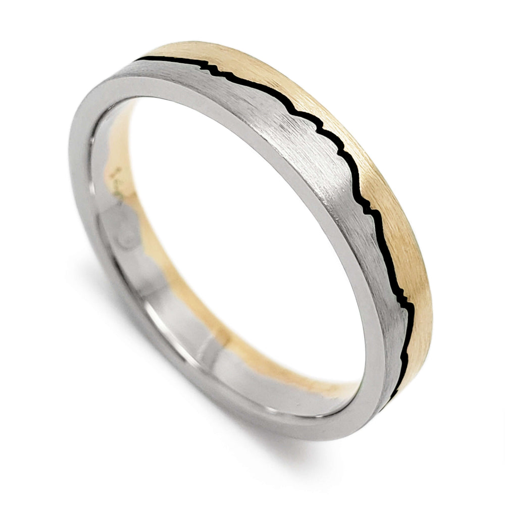 Brushed 14k white and yellow gold wedding ring with mountain range design and blackened groove