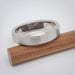 Brushed 14k white gold flat wedding band resting on a cedar box