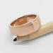 Brushed 14kt rose gold wedding band resting on a pencil