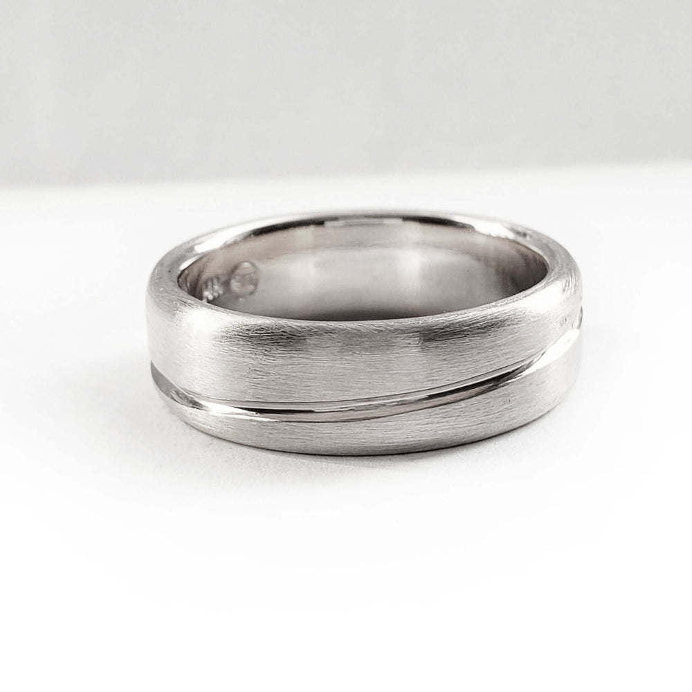 Brushed 14kt white gold wedding band with asymmetrical carved line, side view