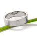 Brushed 14kt white gold wedding band with flat profile resting on a green stem