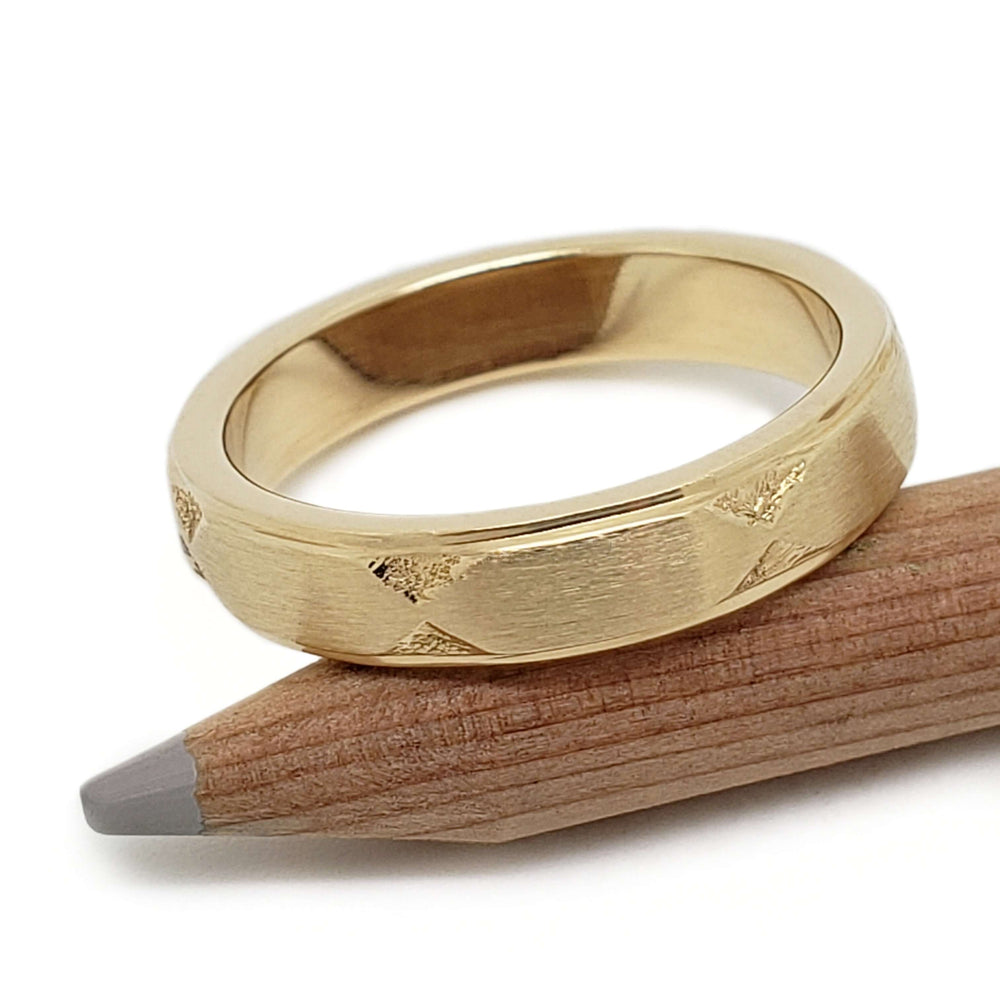 Brushed 14kt yellow gold Art Deco wedding ring resting on a pencil