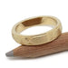 Brushed 14kt yellow gold Art Deco wedding ring resting on a pencil