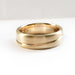 Brushed 14kt yellow gold ring with asymmetrical carved line on white background