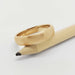 Brushed 14kt yellow gold wedding ring resting on a natural wood pencil