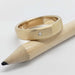 Brushed yellow gold wedding ring with flush-set Canadian diamond, shown on a pencil