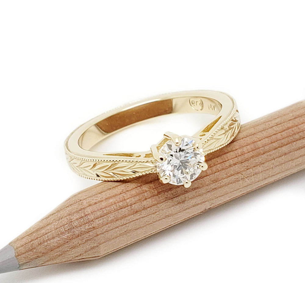 Canadian diamond engagement ring in 14k yellow gold with wheat engraved band, shown on pencil