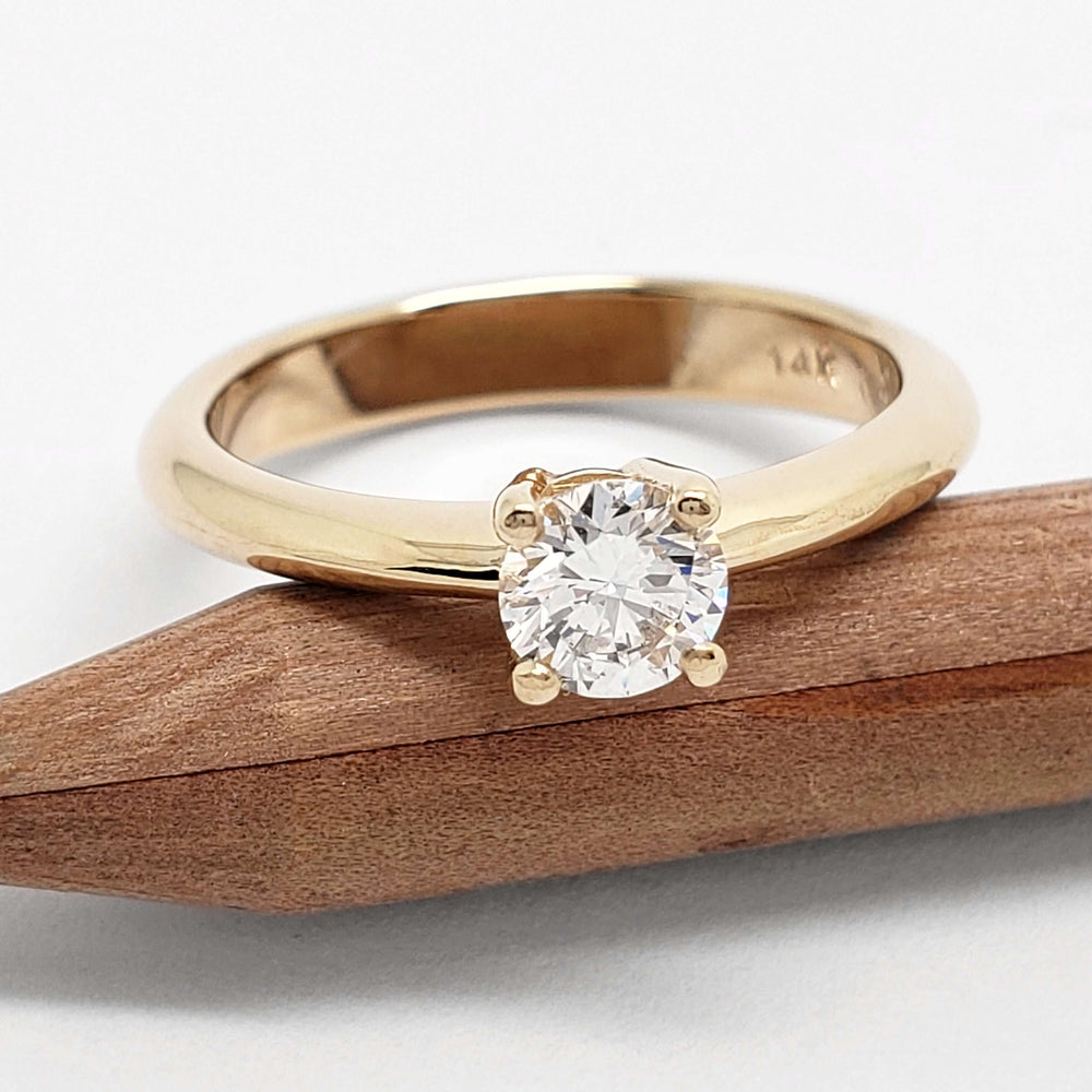 Canadian diamond solitaire ring in 14kt yellow gold, front view on wood