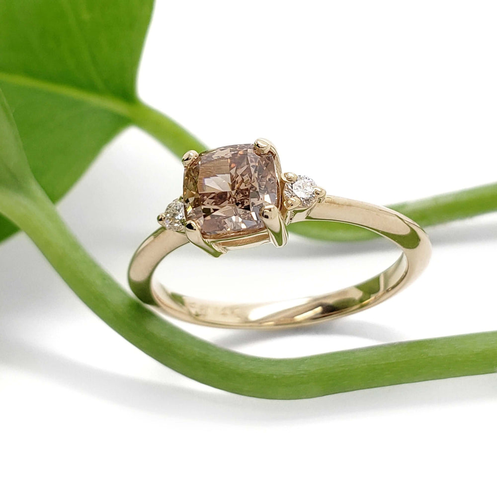 Champagne diamond engagement ring in yellow gold with Canadian side diamonds, styled with greenery