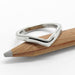 Chevron-shaped 14kt white gold wedding ring with millgrain edge on a pencil