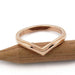 Chevron-shaped 14kt rose gold wedding ring with millgrain edge on wood