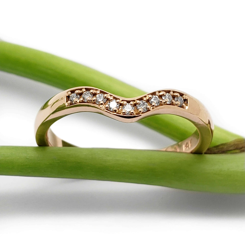 Chevron diamond band in 14kt rose gold displayed on green stems