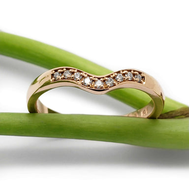 Chevron diamond band in 14kt rose gold displayed on green stems