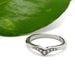 Chevron diamond wedding band in 14kt white gold beside a green leaf