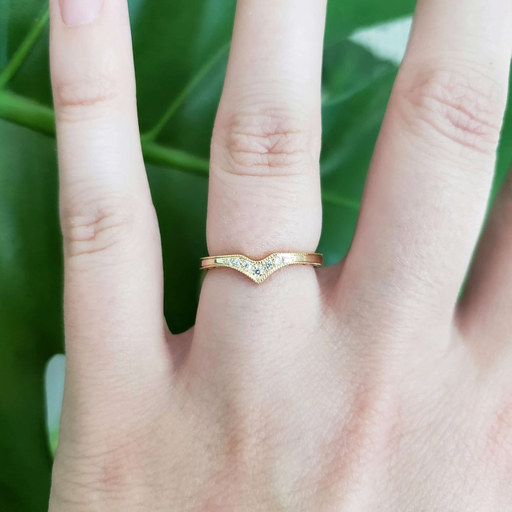 14k yellow gold chevron diamond wedding band shown on a hand