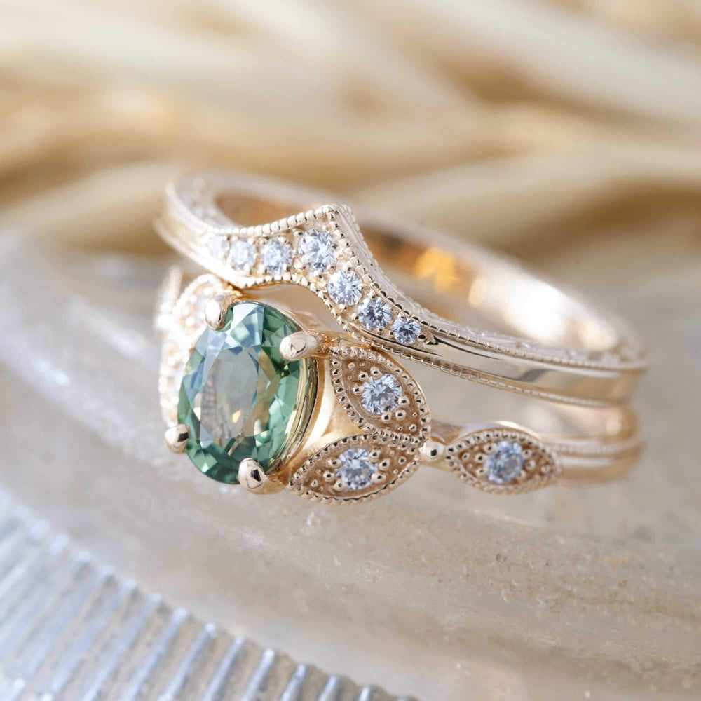 Stacked yellow gold chevron wedding band with diamonds paired with a green sapphire engagement ring