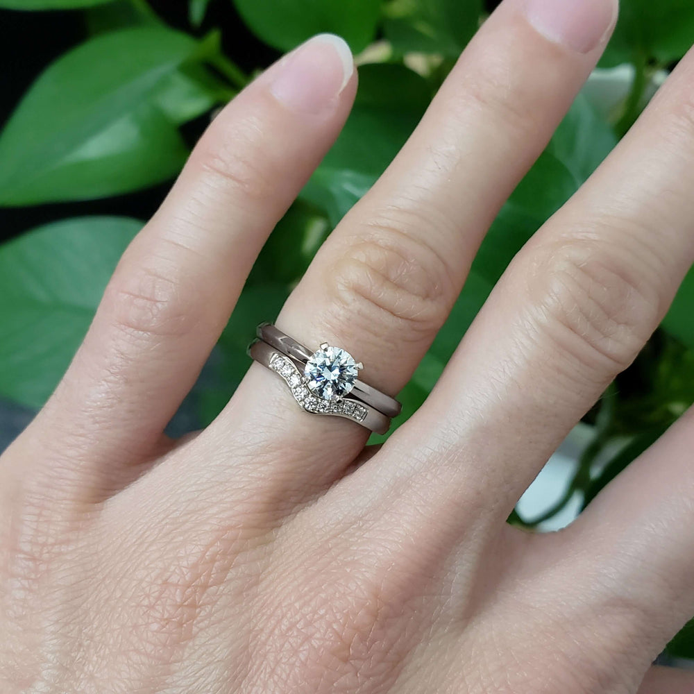 Chevron diamond wedding band stacked with solitaire engagement ring on hand
