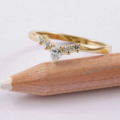 Chevron diamond wedding ring in yellow gold resting on a pencil