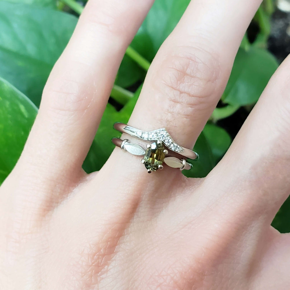 Chevron diamond wedding ring stacked with a gemstone ring on a hand