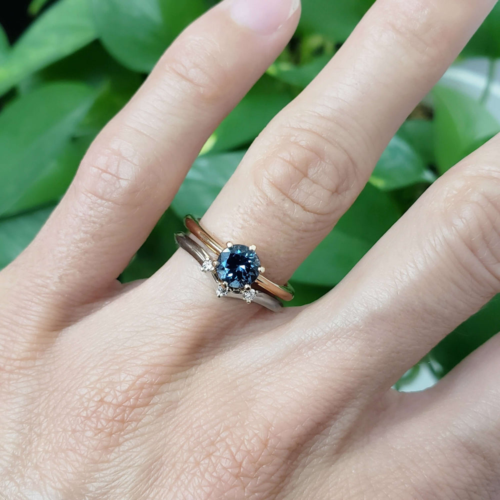 Chevron diamond wedding ring stacked with blue sapphire solitaire and gold band, on hand