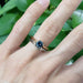 Chevron diamond wedding ring stacked with blue sapphire solitaire and gold band, on hand