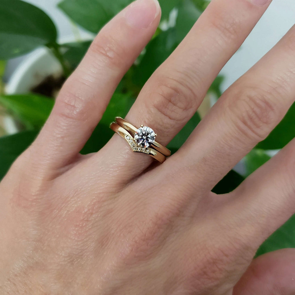 Chevron diamond wedding ring stacked with solitaire engagement ring on a hand
