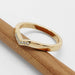 Chevron pavé diamond wedding ring in yellow gold resting on a wooden pencil