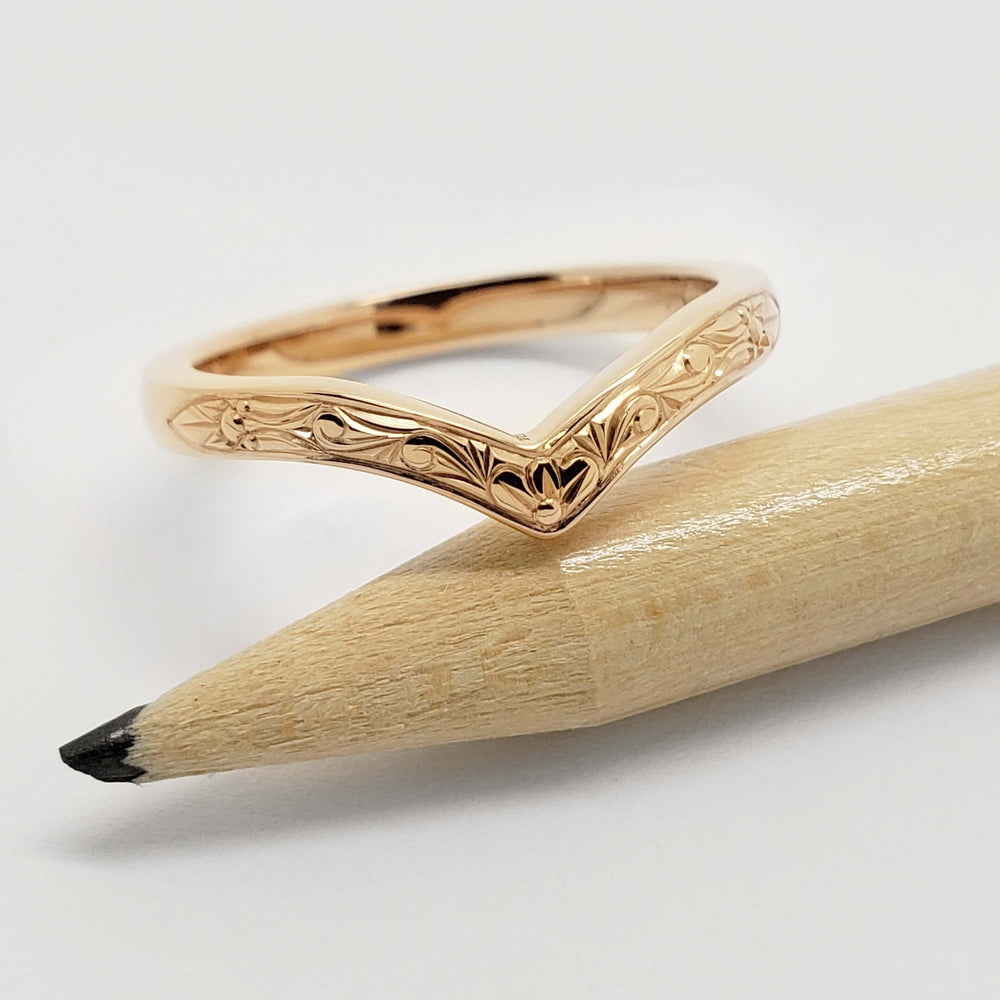 Chevron wedding ring in 14k yellow gold with scroll engraving, shown with pencil