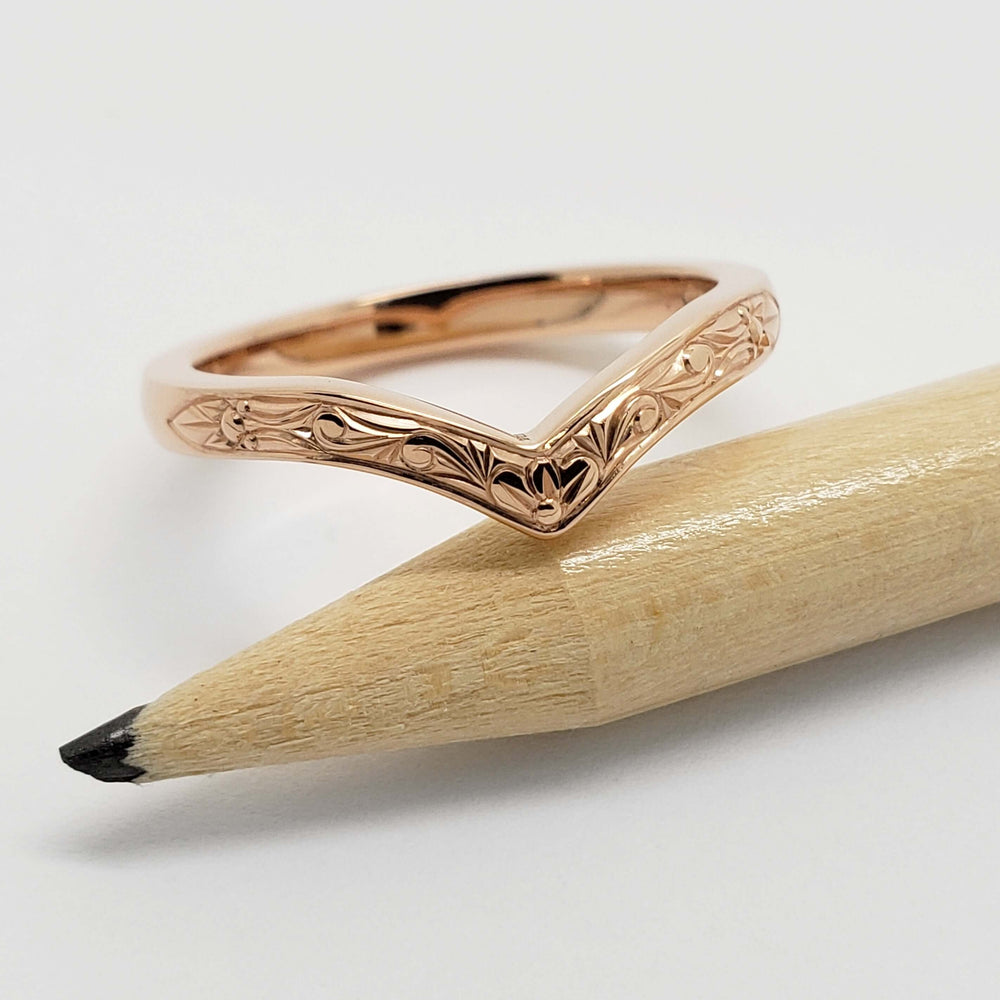 Chevron wedding ring in 14kt rose gold with engraved detail, shown with pencil for scale