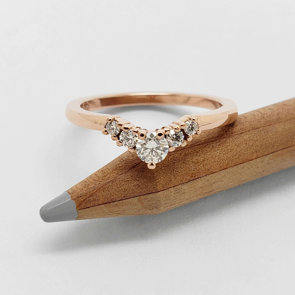 Chevron wedding ring in 14kt rose gold with round diamonds, displayed on a pencil