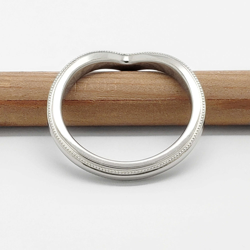 Chevron wedding ring in 14kt white gold with millgrain, top view on a pencil