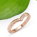 Chevron wedding ring in rose gold with pavé Canadian diamonds beside a green leaf