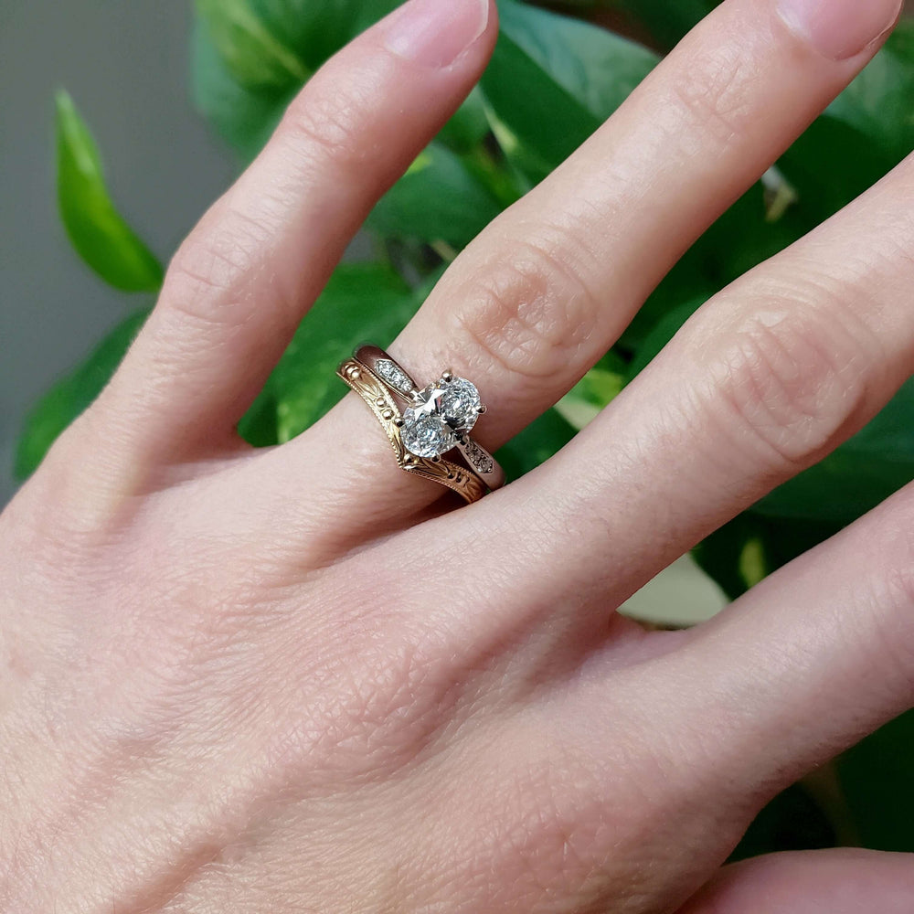 Yellow gold chevron wedding ring stacked with diamond engagement ring on hand