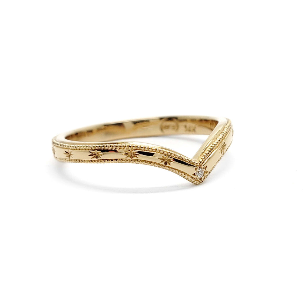 Chevron-shaped yellow gold wedding ring with engraved star details and a central diamond