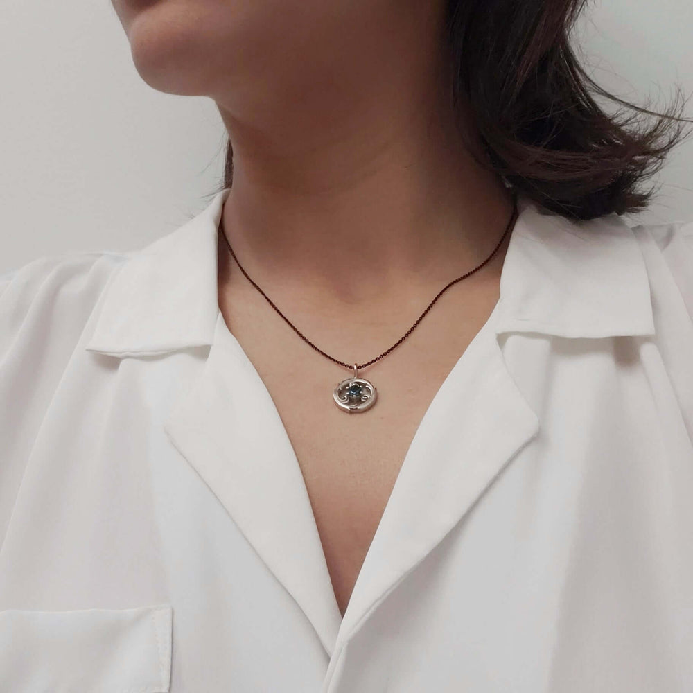 Model wearing a circle vine pendant necklace with a sapphire centerpiece.