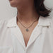 Model wearing a circle vine pendant necklace with a sapphire centerpiece.
