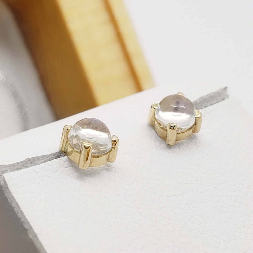 Close-up of 14kt yellow gold moonstone cabochon stud earrings on a white display