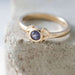 Close-up of 14kt yellow gold ring with bezel-set purple Montana sapphire on stone surface